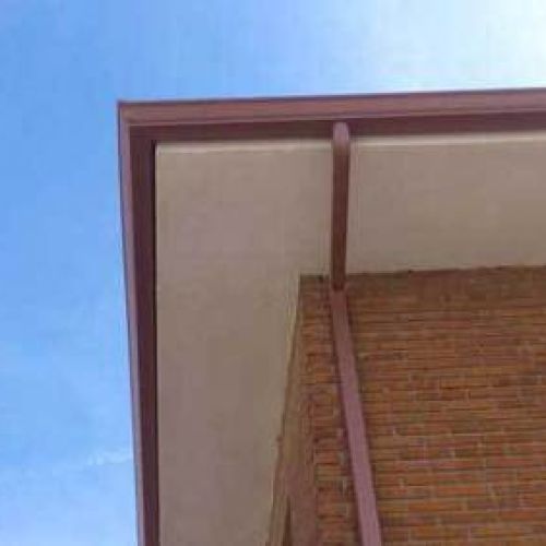 Canalón de chapa en tono granate sobre alero de tejado