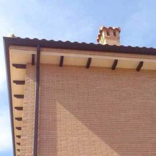 Canalón de chapa en tono marrón sobre alero de tejado