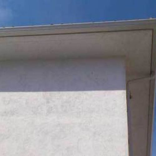 Canalón de chapa en tono gris sobre alero de tejado