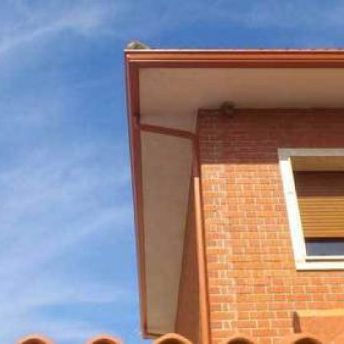 Canalón de chapa en tono cobre sobre alero de tejado