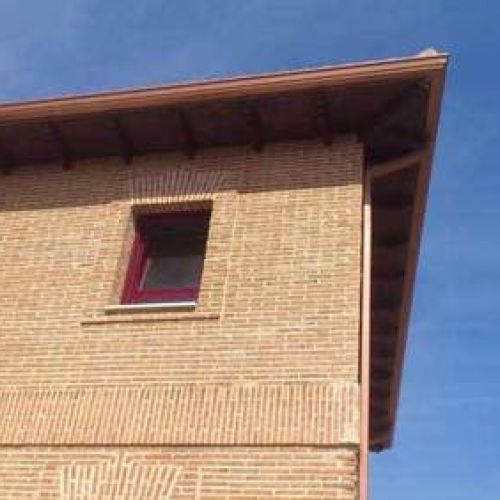 Canalón de chapa en tono cobre sobre alero de tejado