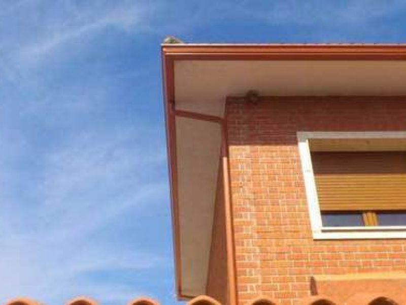 Canalón de chapa en tono cobre sobre alero de tejado